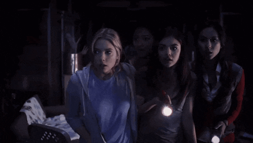 a group of young women are standing in a dark room holding flashlights