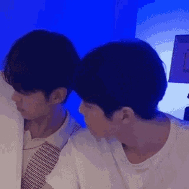 two young men are standing next to each other in a room with blue lights .
