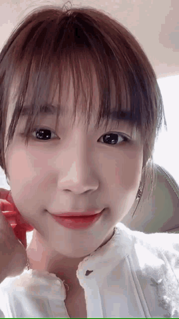 a close up of a young woman 's face with a white shirt on