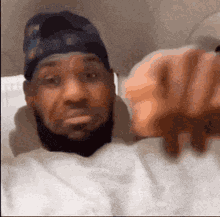 a man with a beard and a hat is taking a selfie with his hand .
