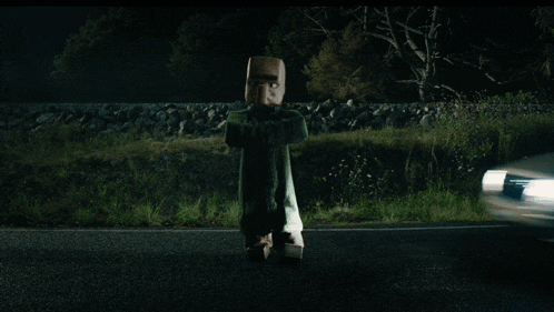 a car is driving down a road at night with a person flying in the air