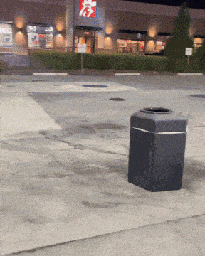 a trash can sits on the sidewalk in front of a chick-fil-a restaurant