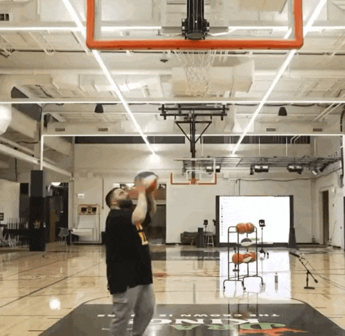 a man throws a basketball in a basketball court with the word kings on the floor
