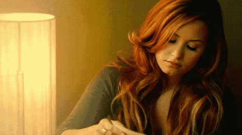 a woman with long red hair is looking down at something