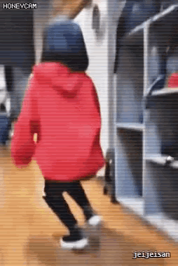 a girl wearing a red jacket and a blue hat is dancing in a hallway