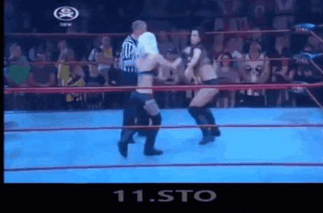 a man and a woman are wrestling in a ring with a referee watching .