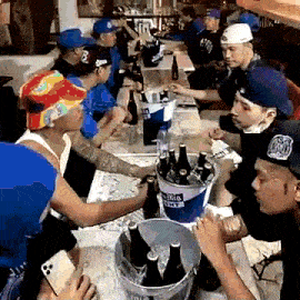 a group of men are gathered around a table with a bucket of miller lite on it