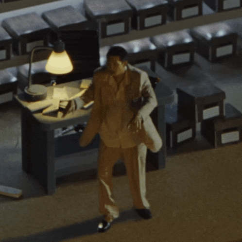 a man in a suit stands in front of a desk with boxes on it