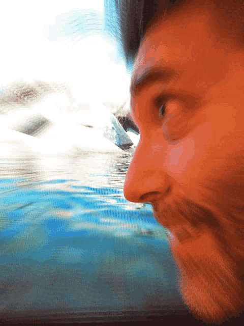 a close up of a man 's face with a blurry background of water
