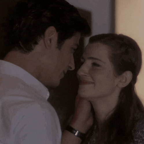 a man is touching a woman 's face and the woman is smiling
