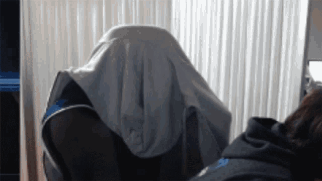 a person sitting in a chair with a blanket covering their head