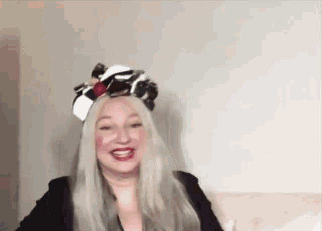 a woman wearing a head scarf and a black jacket is smiling while sitting on a couch .