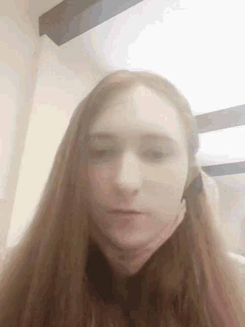 a woman with long red hair is looking at the camera