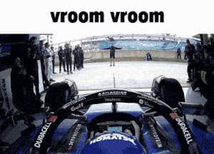a man stands in front of a race car with the words vroom vroom written above him