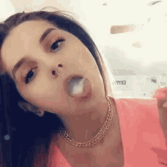 a woman is blowing a bubble with her tongue .