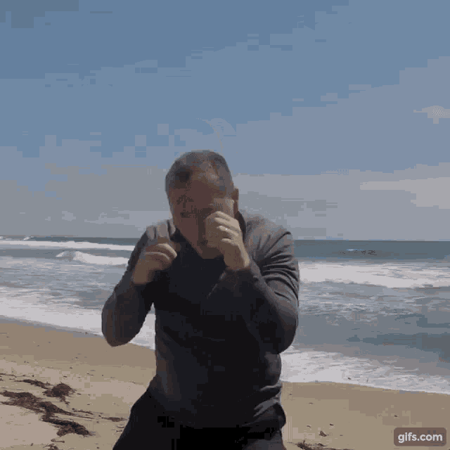 a man standing on a beach with a gifs.com watermark
