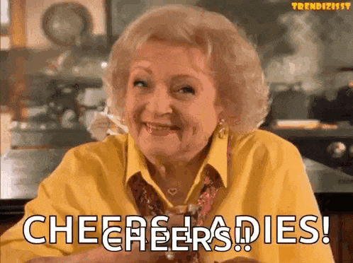 an elderly woman in a yellow shirt is sitting at a table and smiling .