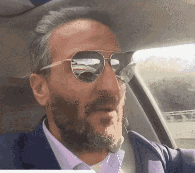 a man with a beard is wearing sunglasses and a suit