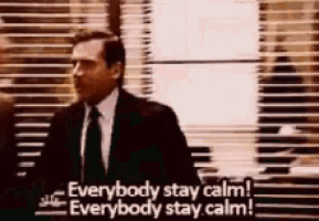 a man in a suit and tie is standing in front of a window with blinds and says everybody stay calm .