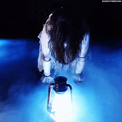 a woman in a white dress is holding a lantern in a dark room with the word choccy wrestling on the bottom right