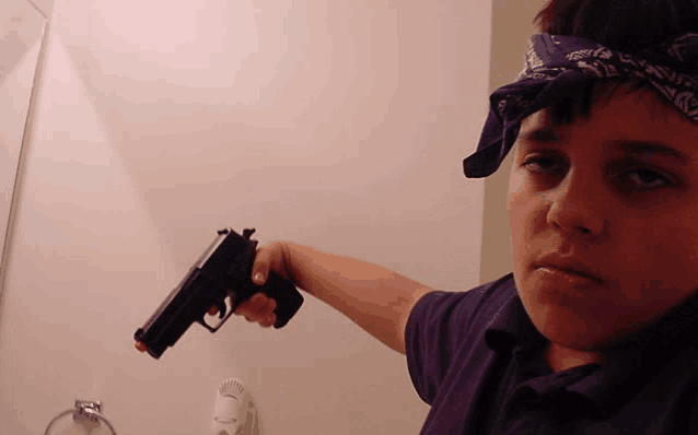a young boy wearing a bandana is pointing a gun
