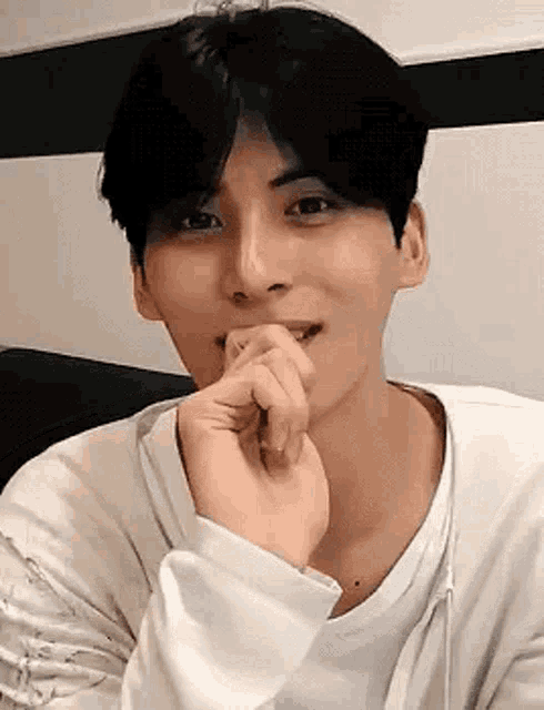 a young man is sitting on a couch with his hand on his chin .