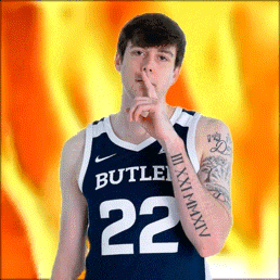 a man wearing a butler basketball jersey holds his finger to his mouth