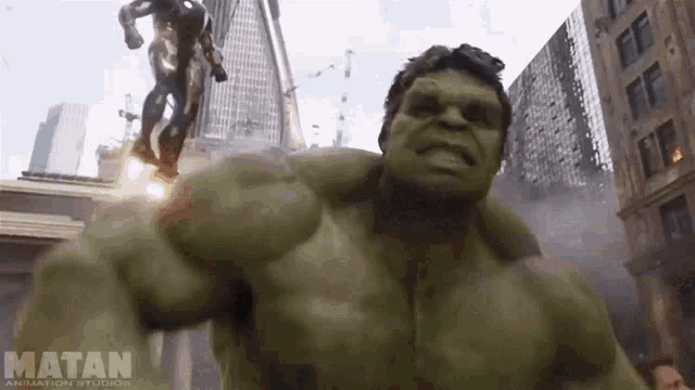 a green hulk is standing in front of a statue of iron man