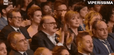 a crowd of people are sitting in a theatre applauding .