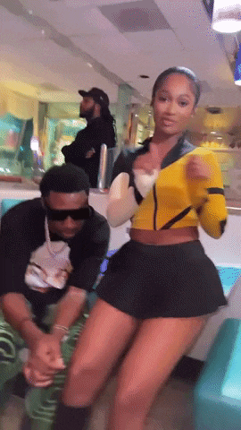 a woman in a yellow top and black skirt is dancing with a man