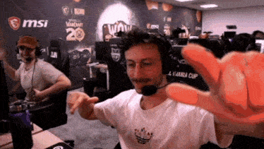 a man wearing a headset is giving a thumbs up in front of a msi wall