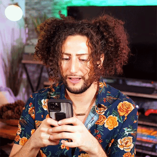 a man with curly hair looks at his phone