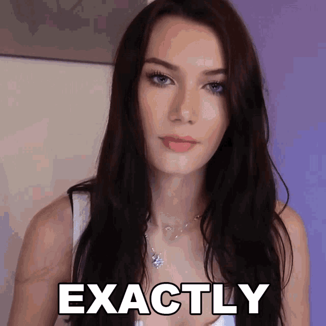 a woman with long dark hair stands in front of a sign that says exactly on it