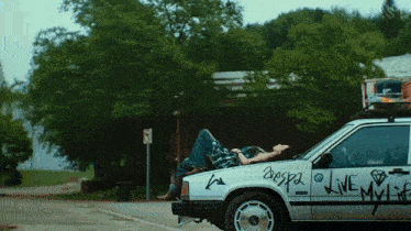 a woman is laying on the hood of a car that has the word live written on it