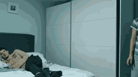 a man laying on a bed with a picture on the wall