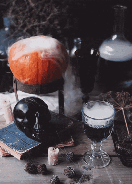 a pumpkin sits on a table next to a glass of wine