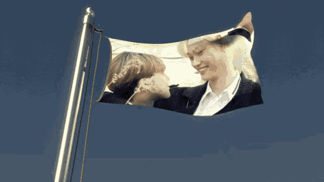 a flag with a picture of two people on it is flying in the wind