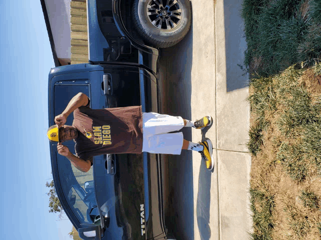 a man is standing in front of a black truck that says titan on the side