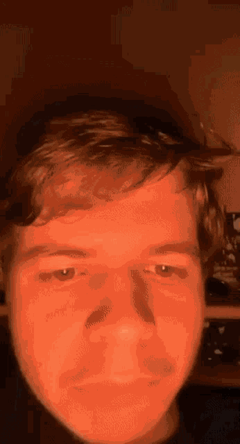 a close up of a man 's face with a red light behind him