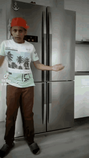 a boy wearing a red hat and a white shirt with the number 15 on it stands in front of a refrigerator