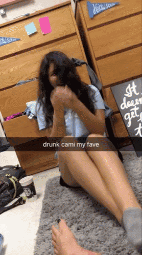 a girl is sitting on the floor with a sign that says drunk cami my fave