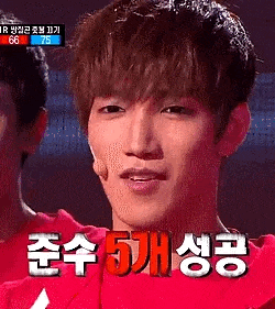 a young man in a red shirt is talking into a microphone while wearing a red shirt with korean writing on it .