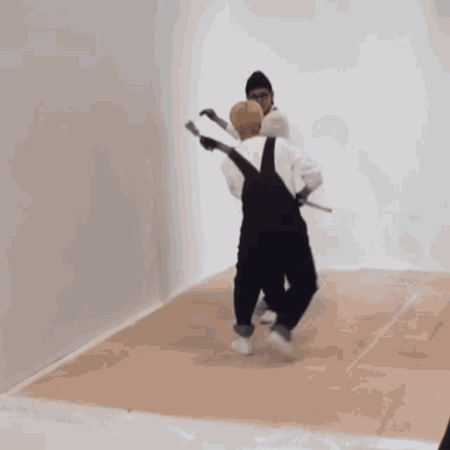 two men in overalls are painting a wall with brushes