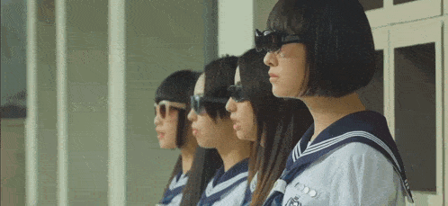 four girls wearing sailor uniforms and sunglasses are standing in a row