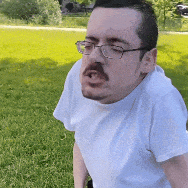 a man wearing glasses and a white shirt is making a funny face