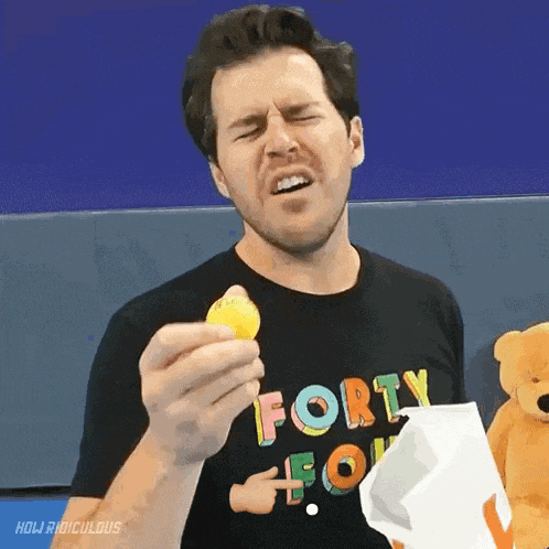 a man wearing a black shirt that says forty four is holding a lemon
