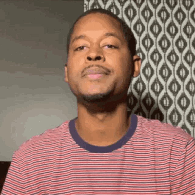 a man wearing a red and white striped shirt is looking at the camera .