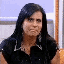 a woman with long dark hair is making a sad face .