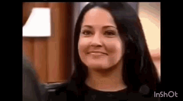 a woman with long black hair is smiling at the camera .