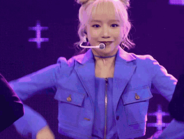 a woman in a blue jacket with a microphone in her mouth is dancing on a stage .